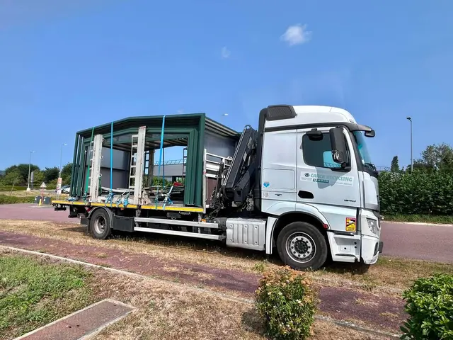 Camion-grue Carca Recycling transportant une structure métallique sanglée