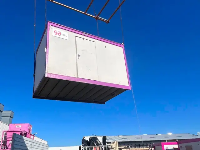 Module préfabriqué suspendu à un palonnier au-dessus d’une aire de chargement