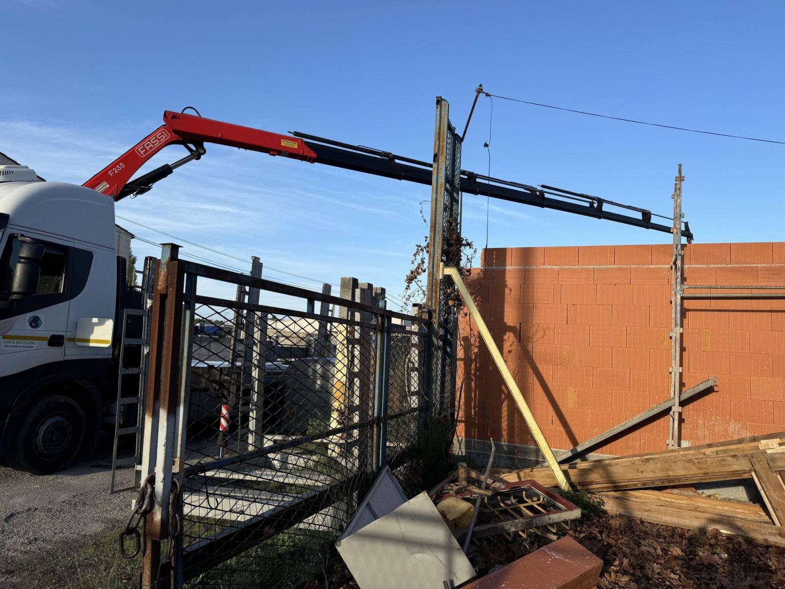 Camion-grue intervenant sur une charpente légère en bois.