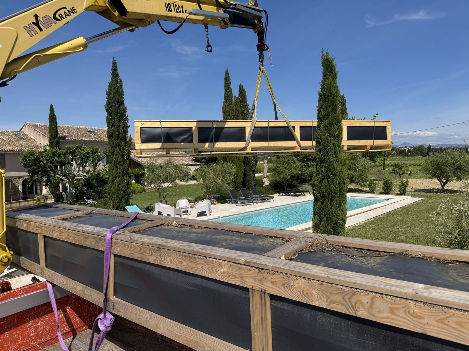 Une longue pièce est soulevée par la grue au-dessus de la piscine.