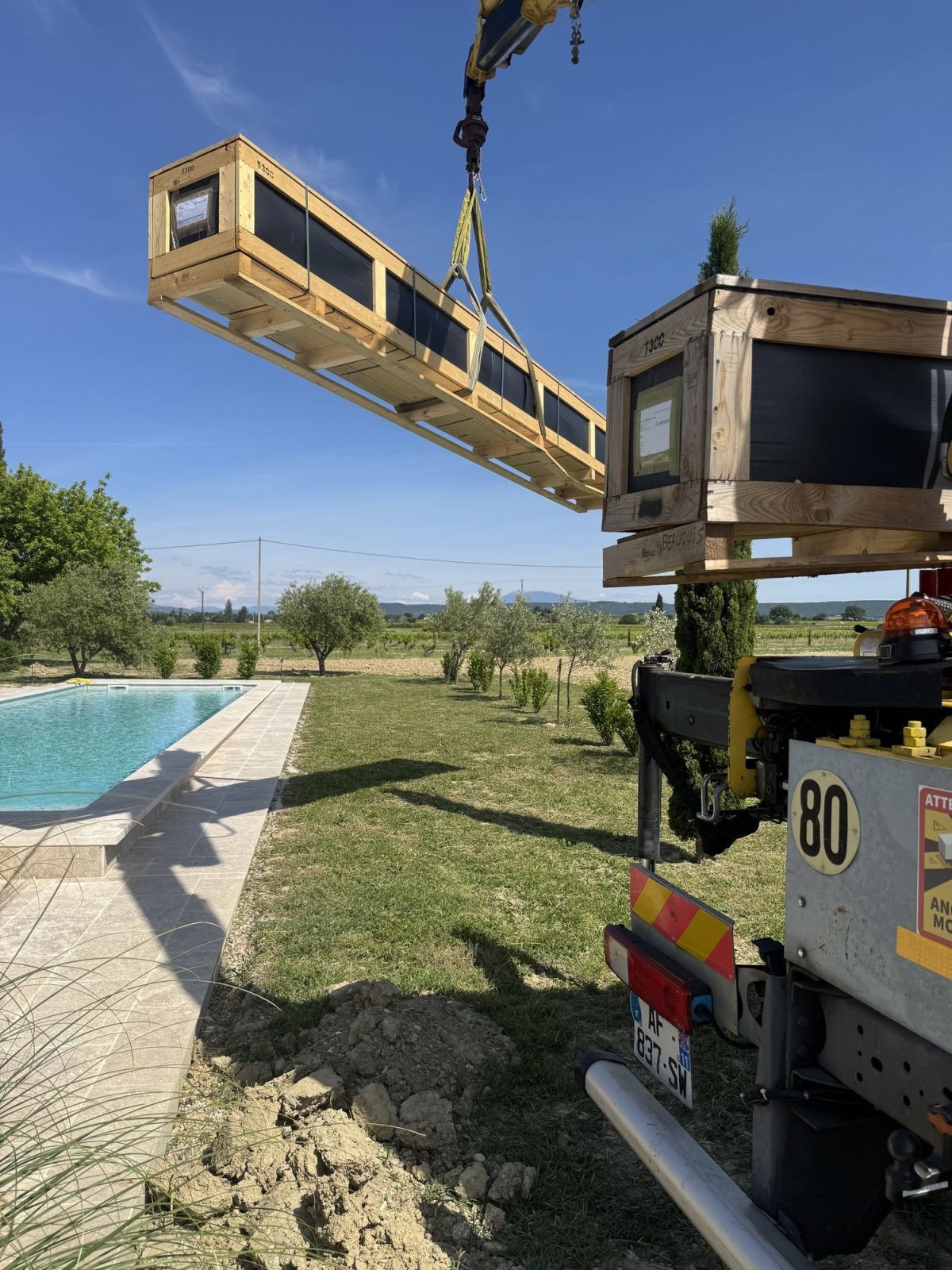 Une longue pièce suspendue à la grue est amenée vers le camion.