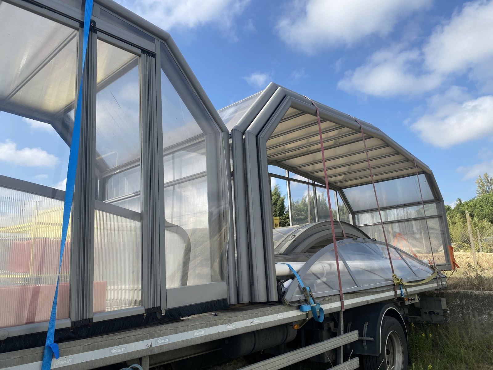 Modules vitrés d’un abri haut maintenus avec des sangles sur le camion.