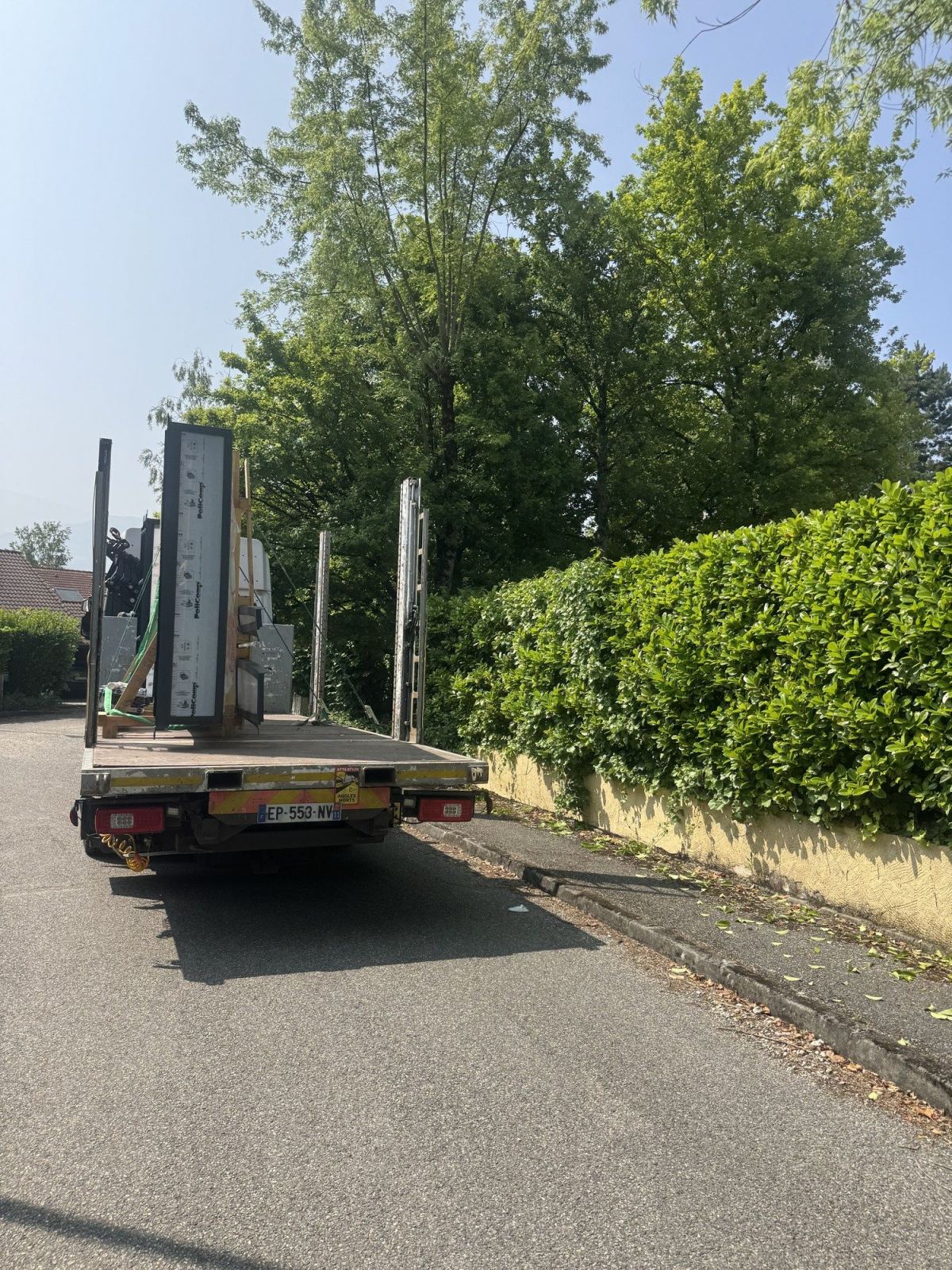 Panneaux vitrés d’un abri chargés et arrimés sur le plateau du camion.