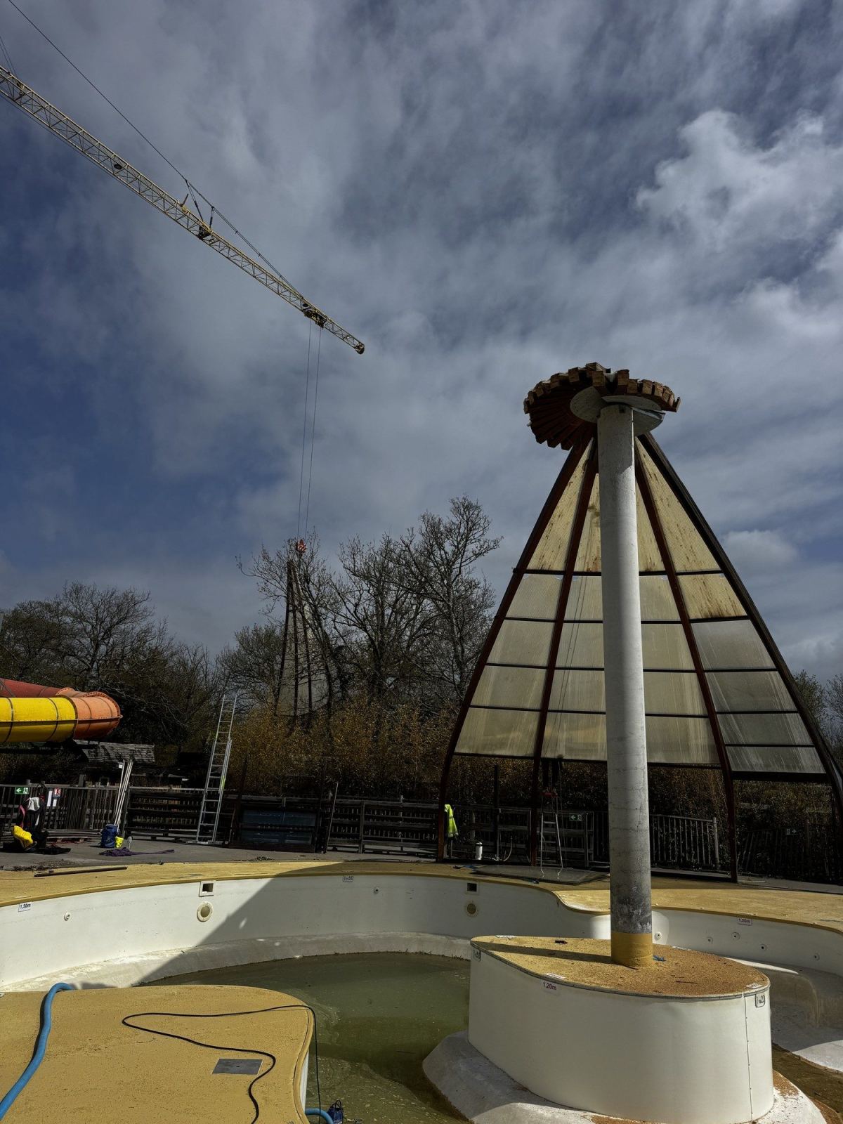 Une portion de la toiture de l’abri circulaire est soulevée par une grue.