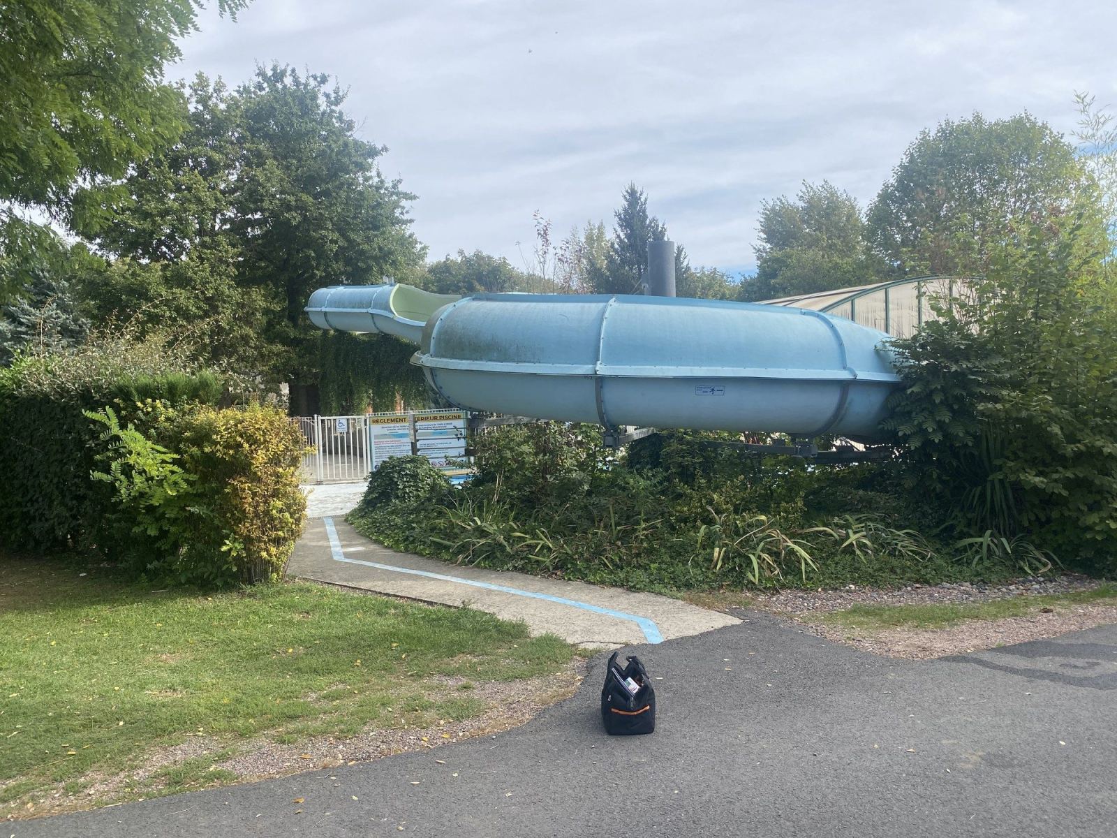 Toboggan aquatique bleu installé dans un espace arboré.