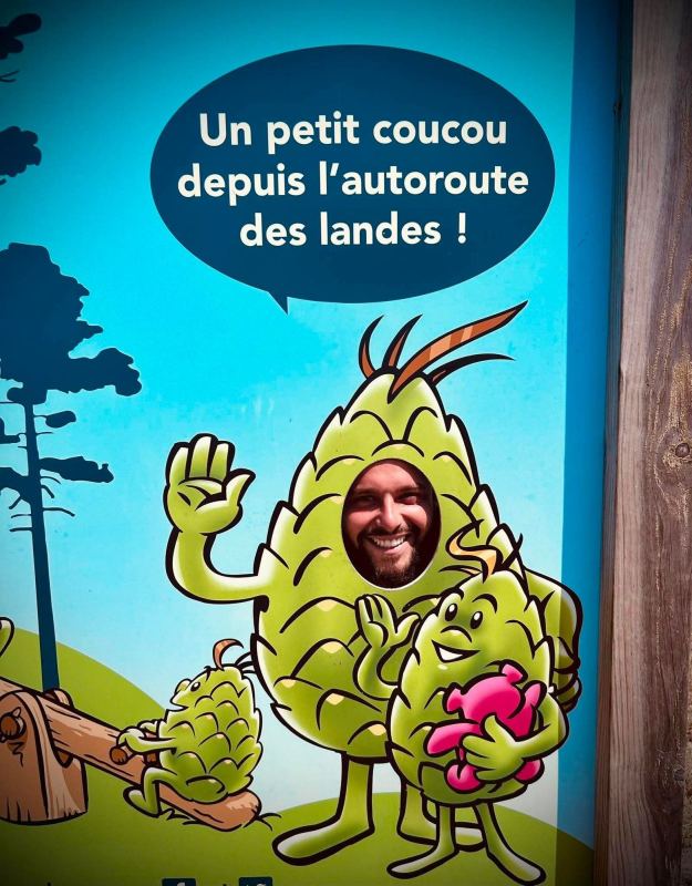 Un membre de l’équipe passe la tête dans un panneau humoristique évoquant l’autoroute des Landes.